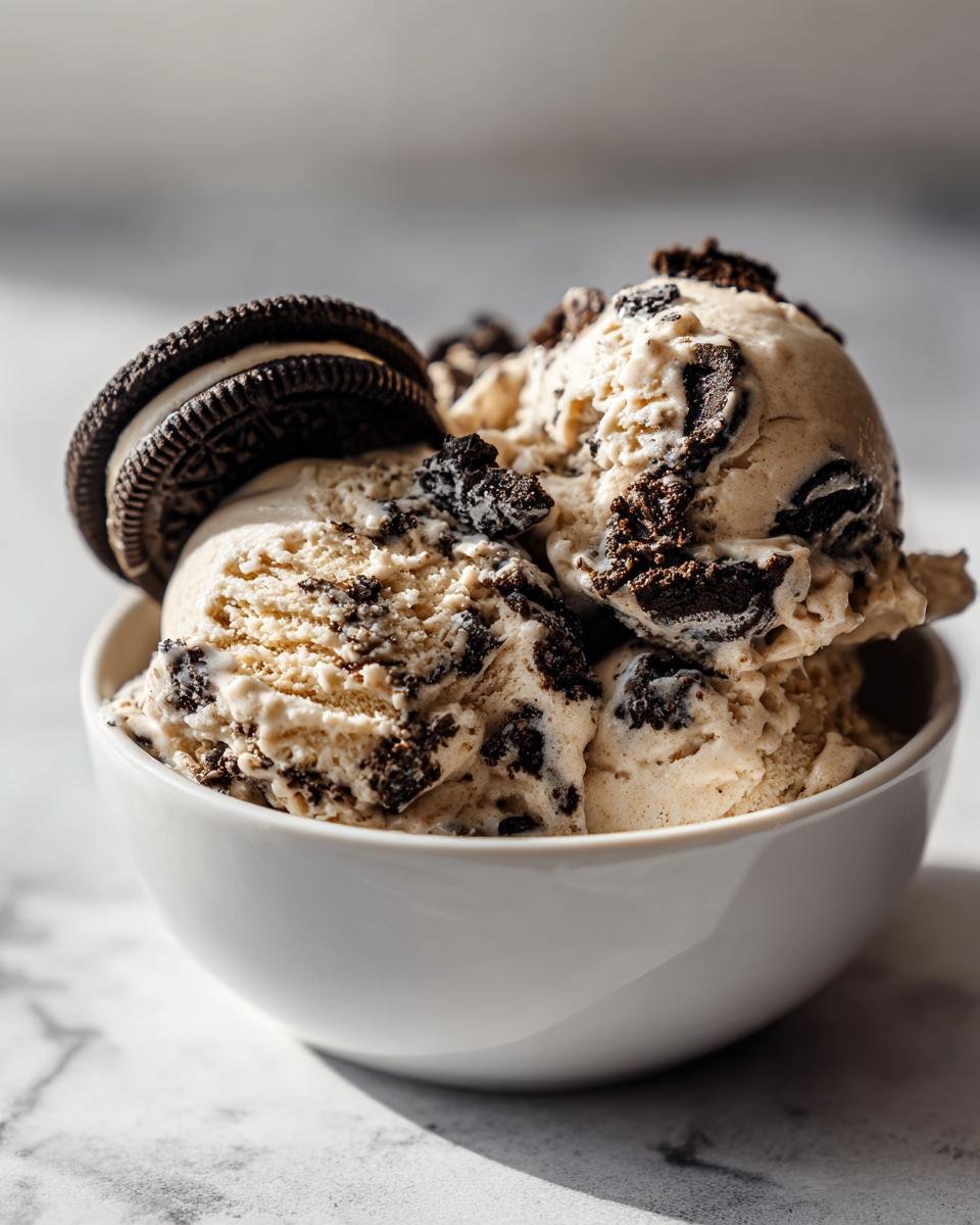 Three scoops of No Churn Peanut Butter Oreo Ice Cream studded with chocolate cookie pieces, topped with a whole Oreo.
