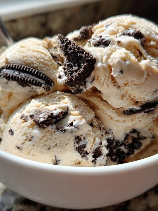 Three scoops of creamy No Churn Peanut Butter Oreo Ice Cream loaded with crushed cookies in a white bowl.