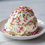 A close-up of two scoops of creamy No Churn Vanilla Ice Cream Rainbow Sprinkles topped generously.