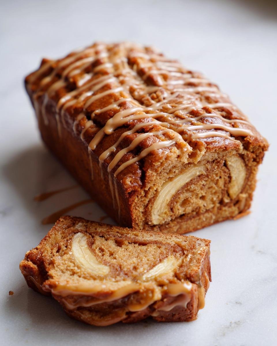 A close-up of a One Layer Banana Biscoff Cake, drizzled with caramel and a slice showing banana pieces.