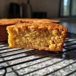 A close-up of a slice of One Layer Maple Sweet Potato Cake on a cooling rack, showing its moist texture.
