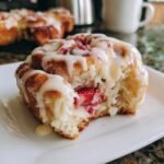 A close-up of a Strawberry Sweet Roll with Lemon Cream Cheese Glaze, showing the fluffy dough and fresh strawberry filling.