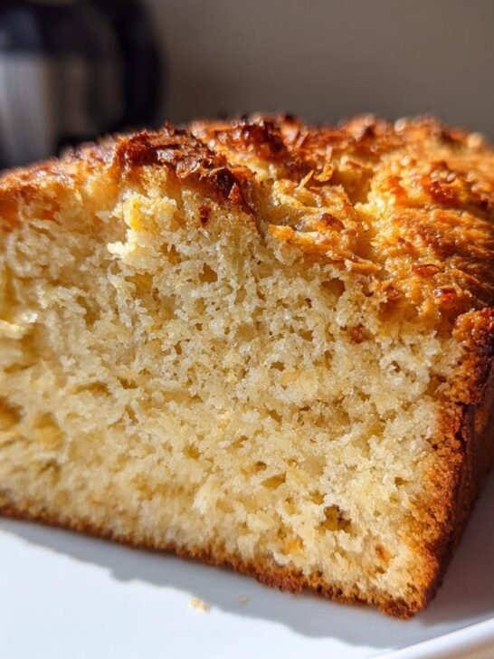 Close-up of a moist slice of Toasted Coconut Bread Gluten Free showing its golden crumb and toasted coconut topping.