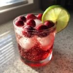 Close-up of the Ultimate Holiday Mocktail garnished with fresh cranberries and a lime wheel.