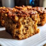 A close-up of a slice of Vegan Apple Oatmeal Sheet Cake, showing its moist texture and chunks of apple and nuts.