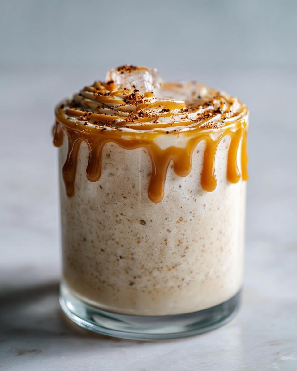 A creamy, frothy Vegan Caramel Eggnog Mocktail topped with whipped topping, caramel drizzle, and spices.