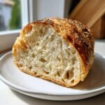 Close-up of the airy crumb structure of Vegan Everything Bagel Brioche Bread, topped with seeds.