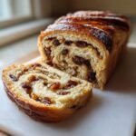 Close-up of a sliced loaf of Vegan Homemade Cinnamon Raisin Bread showing the swirl of cinnamon and plump raisins inside.