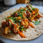 A close-up of a Zesty Chili Lime Chickpea Cauliflower Wrap filled with roasted cauliflower florets and drizzled with sauce.