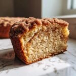A close-up cross-section of a Baked Apple Cider Crumb Donut showing the moist interior and thick cinnamon sugar crumb topping.