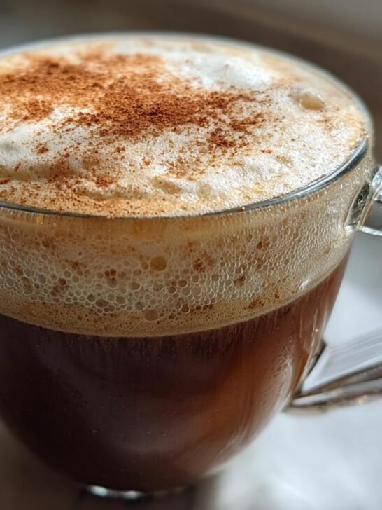 Close-up of a rich Brown Butter Maple Cookie Latte topped with thick foam and cinnamon dust.
