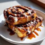 Two stacked Caramel Mocha Cinnamon Rolls drizzled with white icing and sticky caramel sauce.