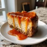 A decadent slice of Caramel Pumpkin Cheesecake Bars topped with thick, dripping caramel sauce on a white plate.