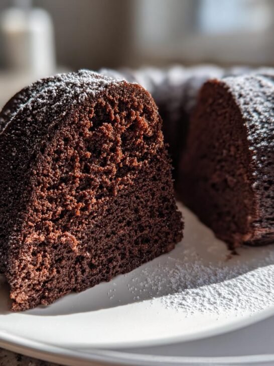 A slice cut from a rich, dark Chocolate Mocha Bundt Cake, dusted lightly with powdered sugar.