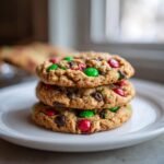 A stack of three chewy Christmas Monster Cookies loaded with chocolate chips and red and green M&Ms.