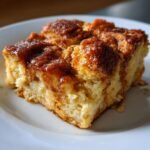 Close-up of a moist square slice of Cinnamon Brown Butter French Toast Casserole on a white plate.