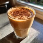 A glass of creamy Cinnamon Maple Eggnog Mocktail topped generously with ground cinnamon or nutmeg.