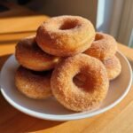 A stack of freshly made Cinnamon Sugar Baked Donuts coated generously in sparkling sugar mixture.