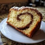 Close-up of a slice of Cinnamon Swirl Eggnog Bread showing a distinct cinnamon swirl pattern and light icing.