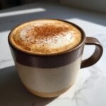 Close-up of a freshly made Cinnamon Toast Latte topped with foamed milk and sprinkled cinnamon.