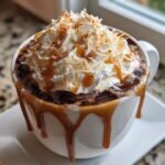 Close-up of a rich Coconut Caramel Hot Chocolate topped with whipped cream, caramel drizzle, and toasted coconut flakes.