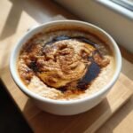 A close-up of creamy Dirty Chai Latte Oatmeal Porridge topped with swirled espresso and cinnamon.