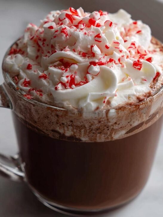 Close-up of an Easy Homemade Peppermint Mocha Latte topped with whipped cream and crushed candy canes.