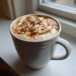 A close-up of an Easy Warm Apple Chai Latte topped with whipped cream, caramel drizzle, and cinnamon.