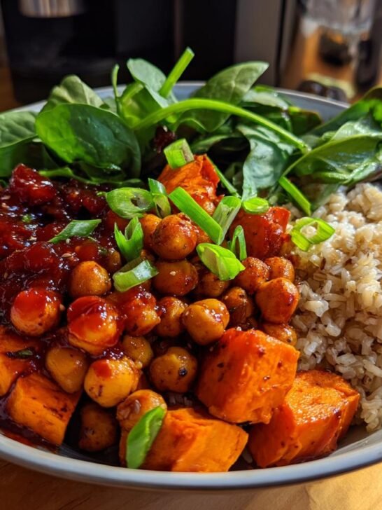 A vibrant Gochujang Sweet Potato Chickpea Bowl featuring brown rice, spinach, and scallions.