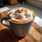 A close-up of a Hot Spiced Gingerbread Latte topped with whipped cream and cinnamon.