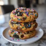 A stack of three thick Oreo Funfetti Chocolate Chip Cookies topped with colorful sprinkles and mini Oreo pieces.
