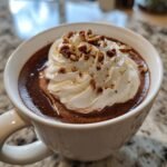Close-up of rich Pecan Praline Hot Chocolate topped with whipped cream and chopped pecans.