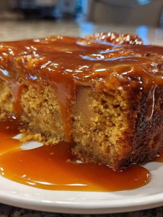 A moist slice of Pumpkin Bread Pudding With Caramel Sauce generously drizzled with thick caramel.