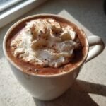 Close-up of Spiced Maple Hot Chocolate topped with whipped cream and a dusting of spice.