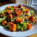 Close-up of a Spicy Chipotle Sweet Potato Chopped Salad featuring vibrant orange sweet potato cubes over greens.
