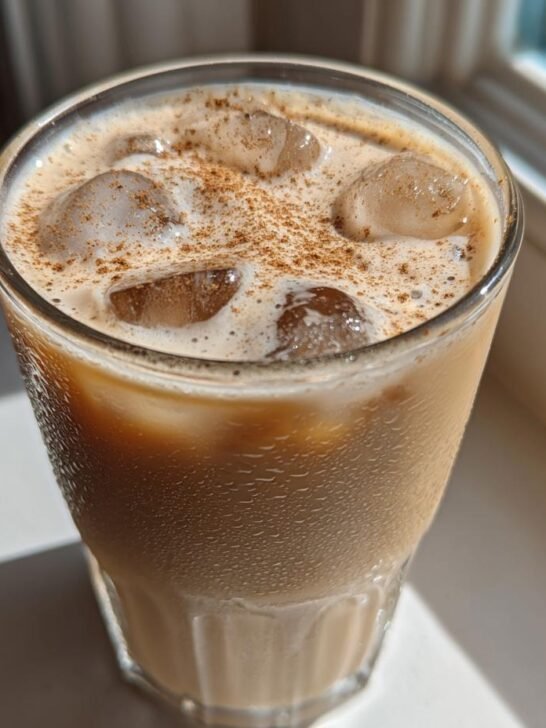 Close-up of a refreshing Vanilla Cinnamon Iced Latte topped with ice cubes and a sprinkle of cinnamon.