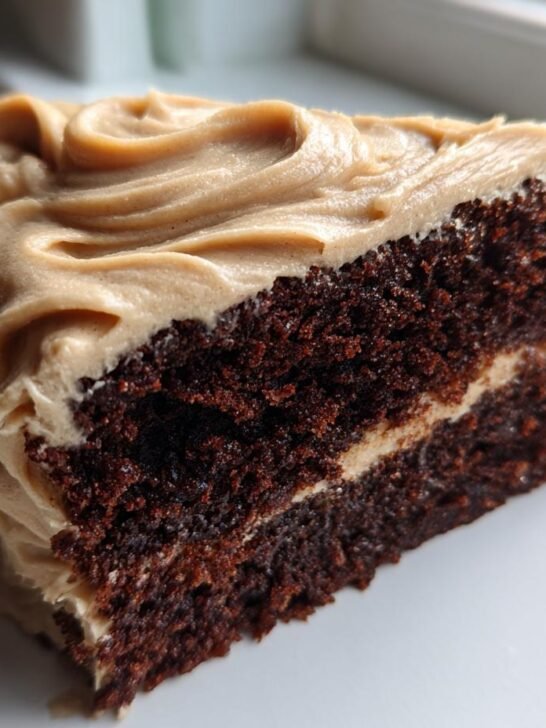 Close-up of a rich, dark slice of Vegan Gingerbread Cake Chai Buttercream frosting.