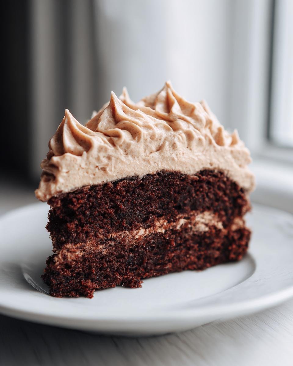 Close-up of a slice of dark Vegan Gingerbread Cake topped with piped Vegan Gingerbread Cake Chai Buttercream.