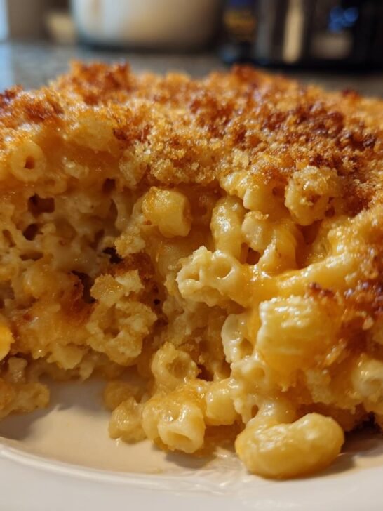 Close-up of a hearty slice of baked mac and cheese showing creamy interior and golden brown, crispy topping.