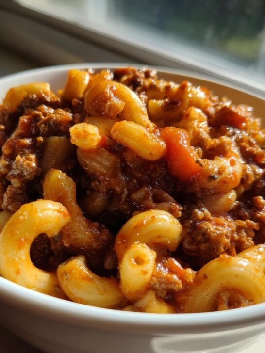 Close-up of a white bowl filled with hearty American Chop Suey featuring elbow macaroni and rich meat sauce.
