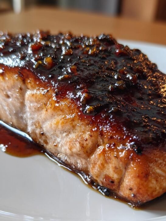 Close-up of a perfectly cooked salmon fillet topped with a thick, dark Bourbon Glazed Salmon sauce.