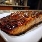 A close-up of a perfectly cooked fillet of Bourbon Glazed Salmon with a shiny, dark glaze.