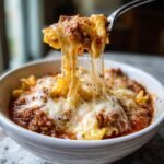 A fork lifting a cheesy, saucy bite out of a bowl of delicious Lasagna Soup, showing long cheese pulls.