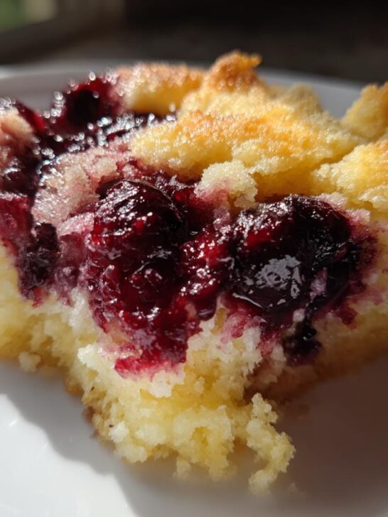 Close-up of a single serving of Cherry Cobbler With Cake Mix, showing the moist yellow cake base and deep red cherry topping.