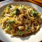 Close-up of creamy Chicken Alfredo With Broccoli tossed with fettuccine pasta and chunks of cooked chicken.