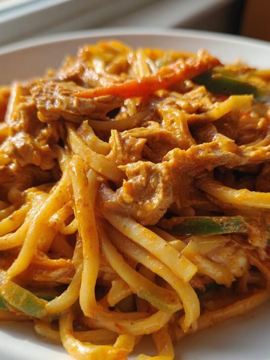 Close-up of a creamy, orange-sauced Chicken Fajita Pasta featuring noodles, chicken strips, and sliced bell peppers.