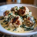 Close-up of browned Creamy Spinach Turkey Meatballs served in a rich, creamy sauce with wilted spinach.