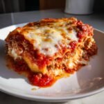 A generous, saucy slice of Crockpot Ravioli Lasagna Casserole topped with melted mozzarella cheese.