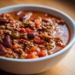 Close-up of a white bowl filled with rich, savory Easy Taco Soup featuring ground meat, kidney beans, and tomatoes.