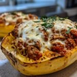 Close-up of a baked Stuffed Spaghetti Squash half filled with meat sauce and topped with melted mozzarella cheese and parsley.